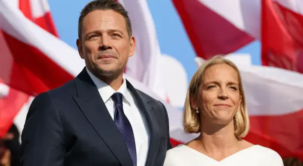 Rafał Trzaskowski z żoną Małgorzatą. W tle polskie flagi.