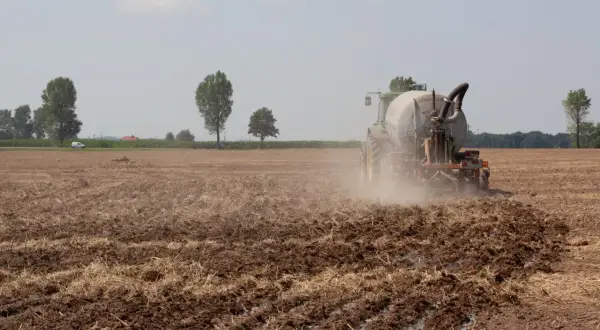 Traktor na polu nawozi ziemię. To obraz tego, co pis zrobił dla polskiej wsi przez 8 lat: nowoczesne rolnictwo i troska o glebę.