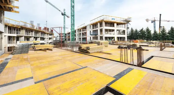 Budowa osiedla w ramach programu mieszkaniowego lewicy: budownictwo społeczne zamiast kredytów. Dźwigi i materiały budowlane na placu budowy.