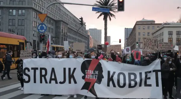 Protest Strajku Kobiet na ulicach Warszawy. Uczestnicy niosą transparent "STRAJK KOBIET". Jak protesty strajku kobiet wpłynęły na poparcie PiS?