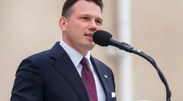 Sławomir Mentzen w garniturze przemawia do mikrofonu. Jego majątek budzi zainteresowanie.