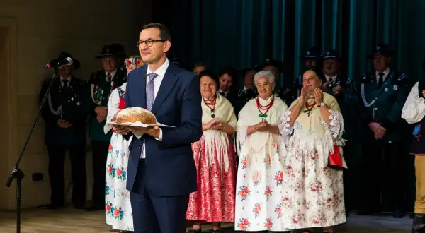 Mateusz Morawiecki z bochenkiem chleba, w otoczeniu osób w strojach ludowych. Kto zyskał najwięcej na rządach prawa i sprawiedliwości?