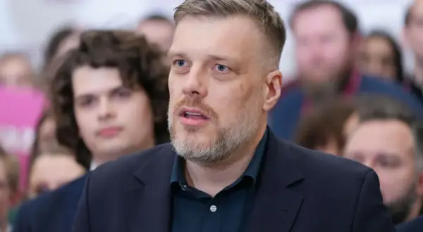 Adrian Zandberg, z charakterystyczną brodą, przemawia. Dlaczego Adrian Zandberg nie wszedł do rządu Donalda Tuska? Pytanie wciąż budzi dyskusje.