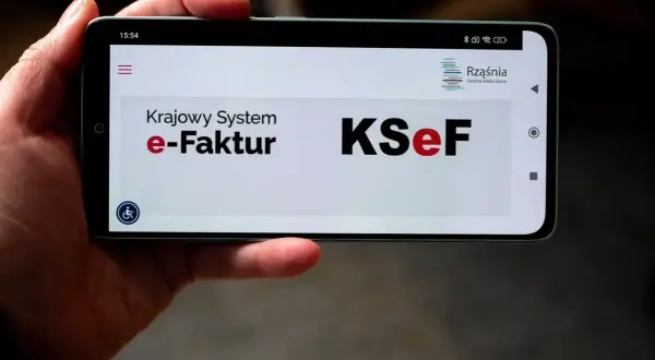 Dłoń trzyma smartfon z widocznym ekranem logowania do KSeF. Użytkownik napotyka problem z logowaniem do Krajowego Systemu e-Faktur.