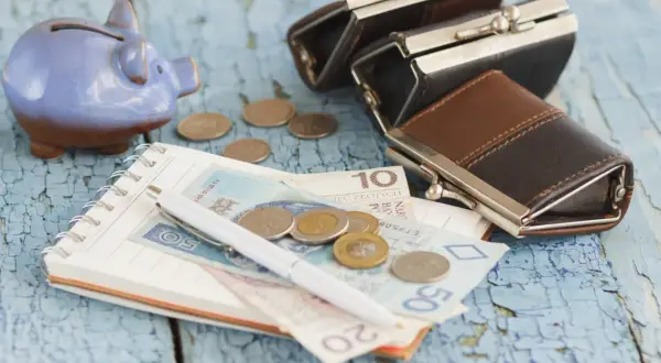 Świnka-skarbonka, portmonetki, notatnik z pieniędzmi i monetami. Zastanawiasz się, ile wynosi zasiłek dla bezrobotnych?