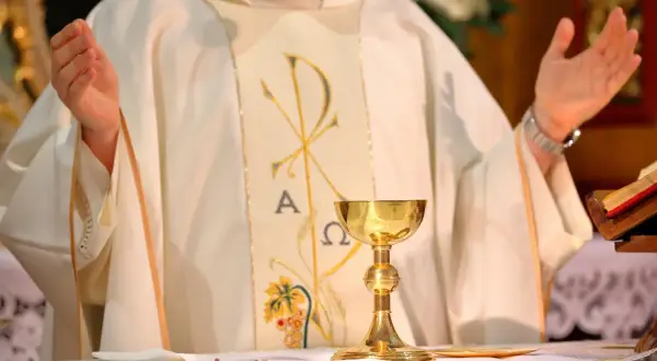Ksiądz w białej szacie z symbolem Chi-Ro, kielich mszalny. Dyskusja o likwidacji funduszu kościelnego, renegocjacji konkordatu i postulatach lewicy.