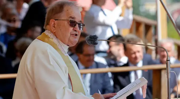 Ojciec Tadeusz Rydzyk przemawia do mikrofonu. W tle widać ludzi, a także fragmenty budowli. W czasach rządu PiS, fundacje związane z ojcem Rydzykiem otrzymywały znaczące dotacje.