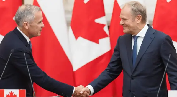Dwóch polityków ściska sobie dłonie na tle flag Kanady. Wzmocnienie relacji polska-kanada.