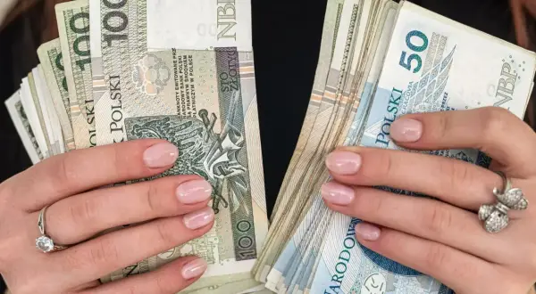 Dłonie z paznokciami pomalowanymi na jasny róż trzymają stosy polskich złotówek. W jednej ręce banknoty 100 zł, w drugiej 50 zł. To pewnie babciowe na drobne wydatki.