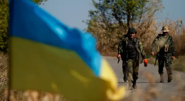 Ukraińska flaga na pierwszym planie, za nią dwaj żołnierze idący drogą. Hasło "stop ukrainizacji Polski" budziło kontrowersje, a Konfederacja używała go w swojej retoryce.
