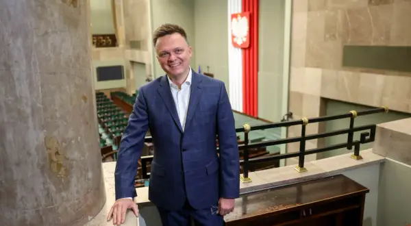 Szymon Hołownia jako Marszałek Sejmu: ocena jego kadencji i potencjalne wpadki. Uśmiechnięty polityk w garniturze na tle sali sejmowej.
