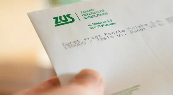Dłoń trzyma dokument ZUS. Konfederacja i dobrowolny ZUS dla firm – dokładne kalkulacje są kluczowe dla przedsiębiorców.