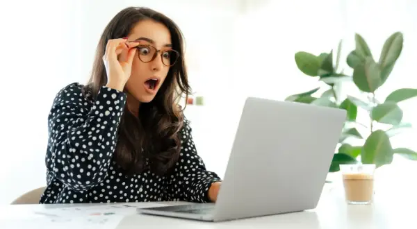 Zaskoczona kobieta w okularach patrzy na laptopa. Czyżby właśnie dowiedziała się, że od kiedy 35 dni urlopu?