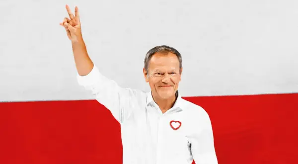 Donald Tusk z podniesioną ręką, symbolizującą zwycięstwo, na tle flagi Polski. Jego biała koszula z sercem i uśmiech podkreślają pozytywny przekaz. Polityka zagraniczna Koalicji Obywatelskiej w jego wizji.