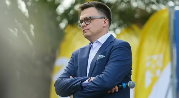 Mężczyzna w garniturze, z okularami, z mikrofonem w dłoni. Symboliczne przedstawienie debaty: Polska 2050 vs Nowa Lewica, główne osie sporu ideologicznego.