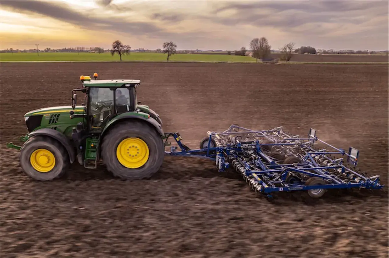 Zielony traktor z agregatem uprawowym na polu. Europejski zielony ład: dlaczego lewica popiera unijną politykę klimatyczną.