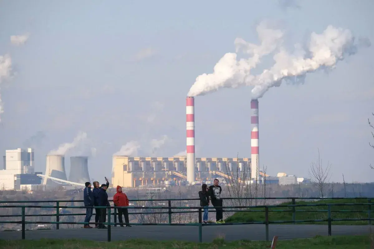 Dymiące kominy elektrowni. Polska 2050: transformacja węglowa koszty i terminy. Ludzie obserwują przemysł.