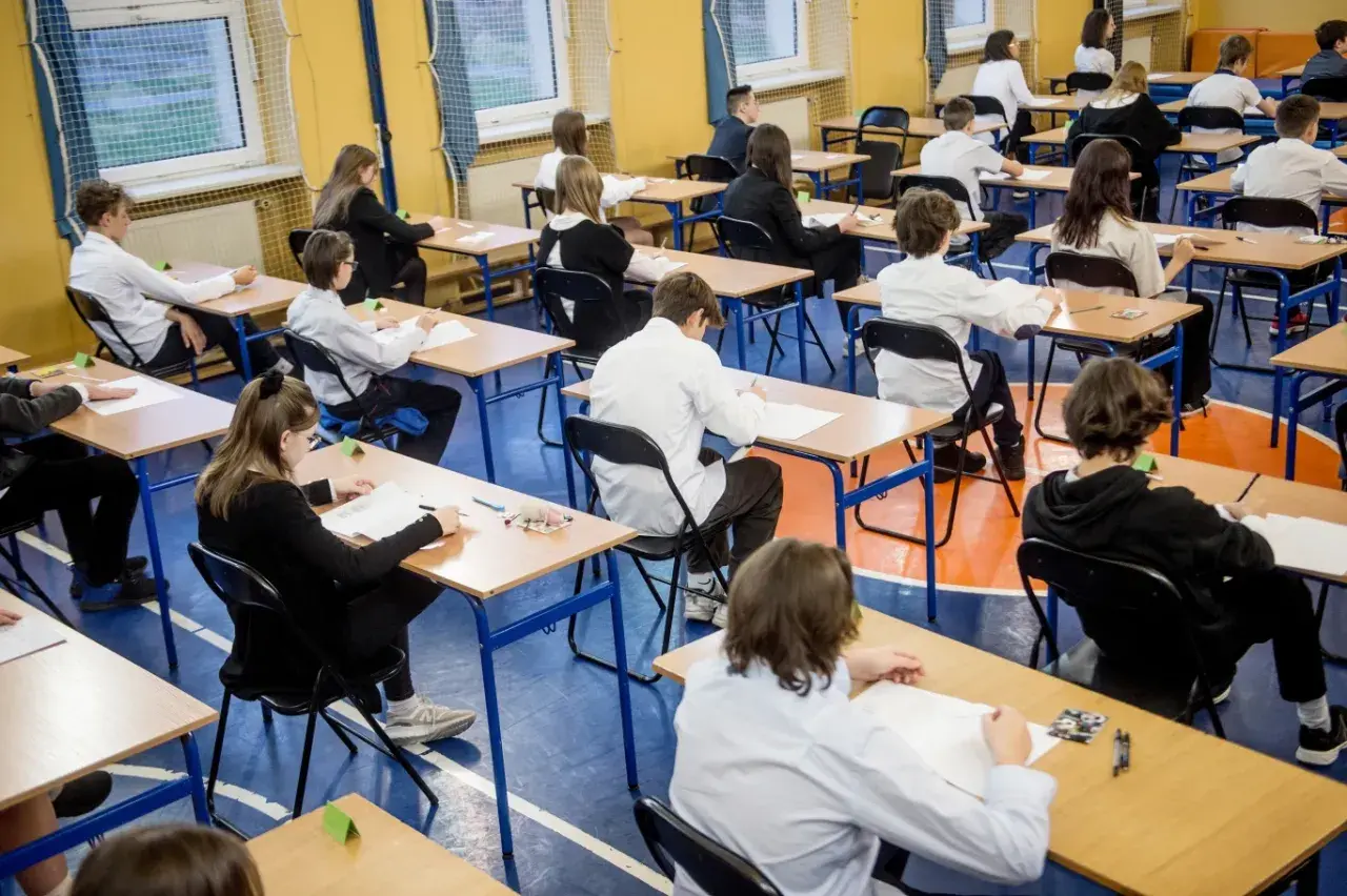 Uczniowie w skupieniu piszą egzaminy ósmoklasisty w sali gimnastycznej. Cisza i powaga towarzyszą temu ważnemu dniu.