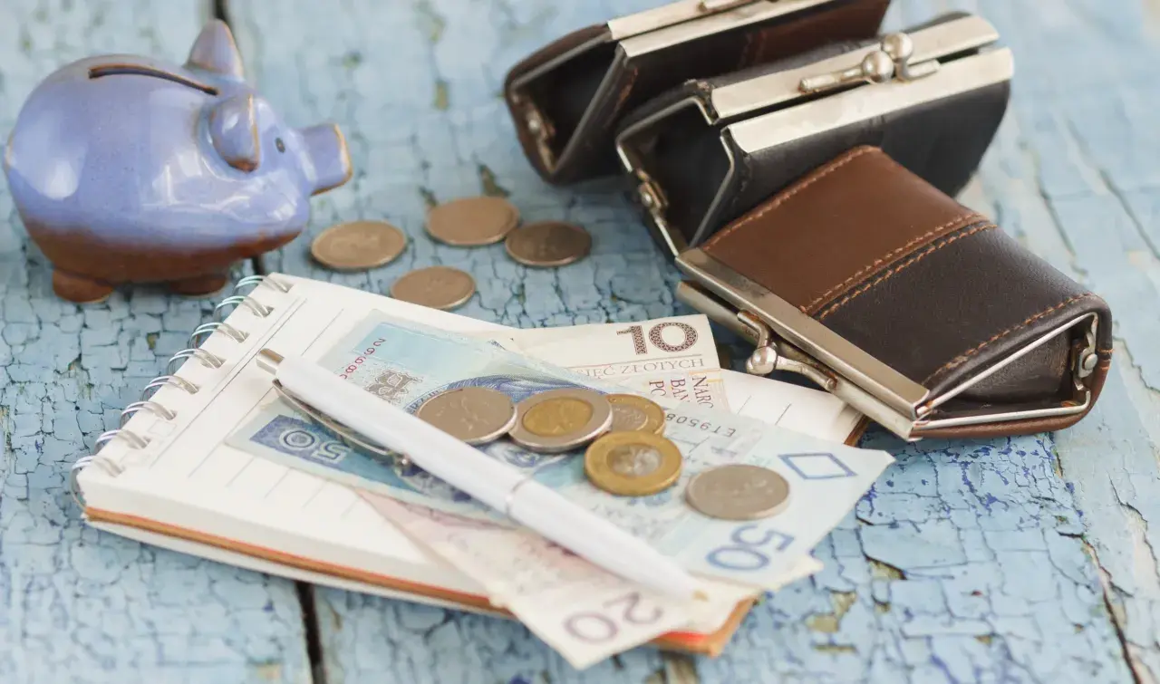 Świnka-skarbonka, portmonetki, notatnik z pieniędzmi i monetami. Zastanawiasz się, ile wynosi zasiłek dla bezrobotnych?