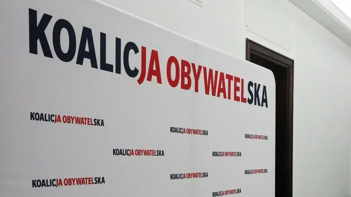 Białe tło z napisem "KOALICJA OBYWATELSKA" w dużych, czerwono-granatowych literach. Pod spodem powtarza się mniejszy napis. To symboliczne tło dla dyskusji o stosunku Koalicji Obywatelskiej do Europejskiego Zielonego Ładu.