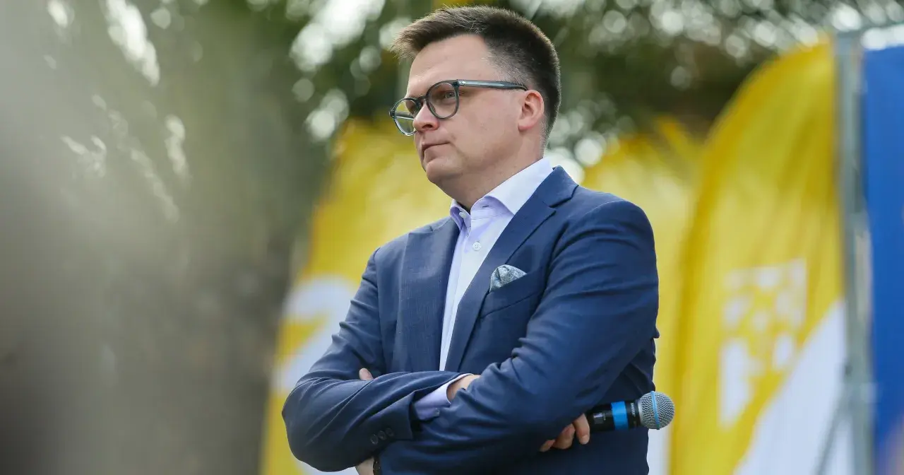 Mężczyzna w garniturze, z okularami, z mikrofonem w dłoni. Symboliczne przedstawienie debaty: Polska 2050 vs Nowa Lewica, główne osie sporu ideologicznego.