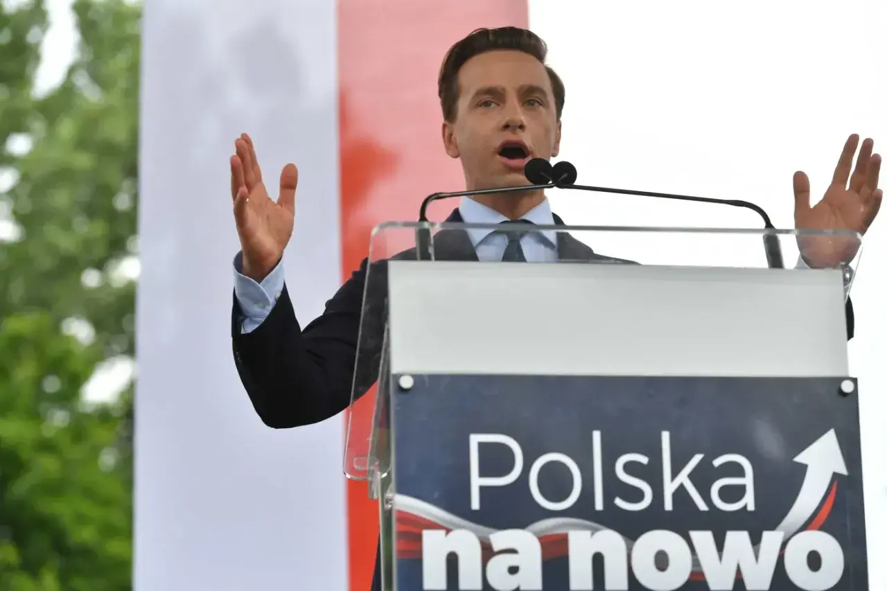 Mężczyzna przemawia przy mównicy z napisem "Polska na nowo". Konfederacja a podatki – chce znieść PIT, CIT i VAT, by uwolnić gospodarkę.