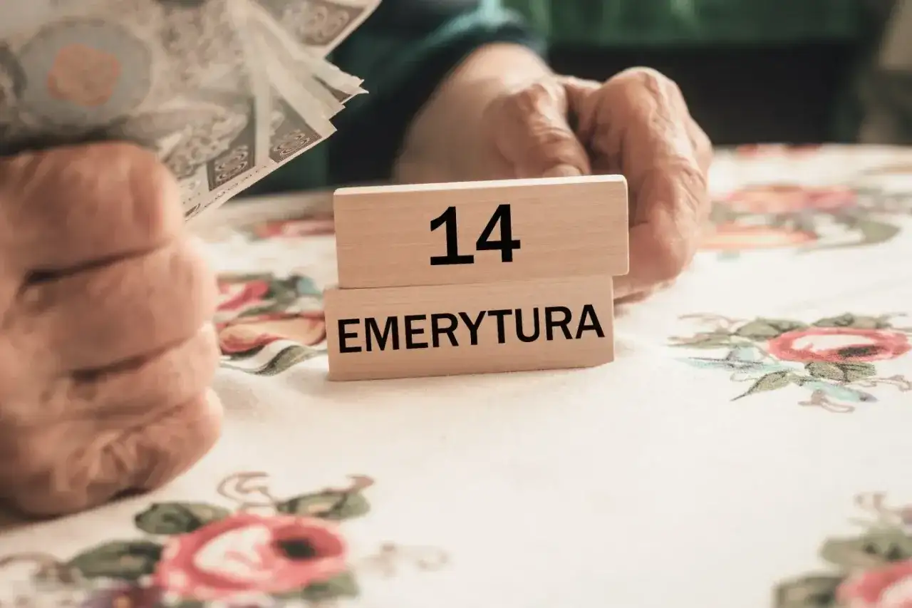 Dłonie trzymają pieniądze obok drewnianych klocków z napisem "14 EMERYTURA".