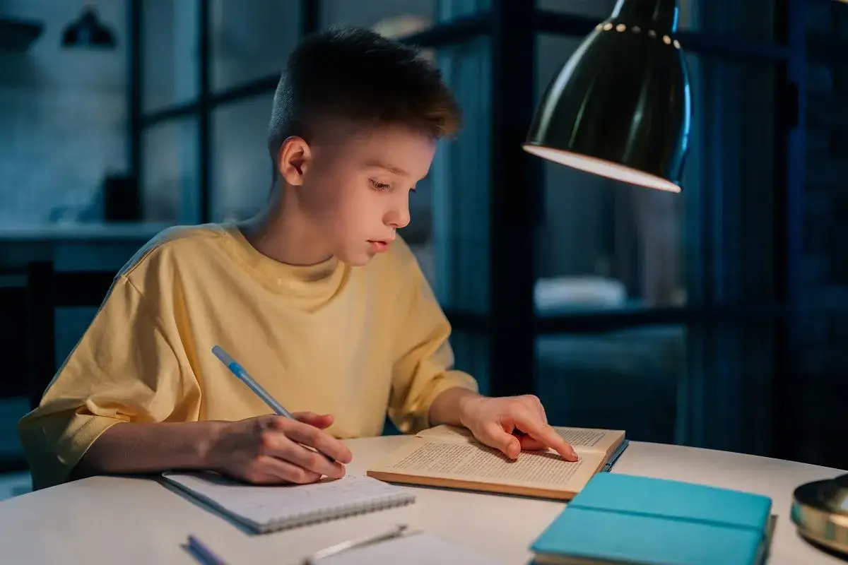 Chłopiec uczy się wieczorem. Czy ministerstwo edukacji w rękach koalicji obywatelskiej oznacza likwidację prac domowych?