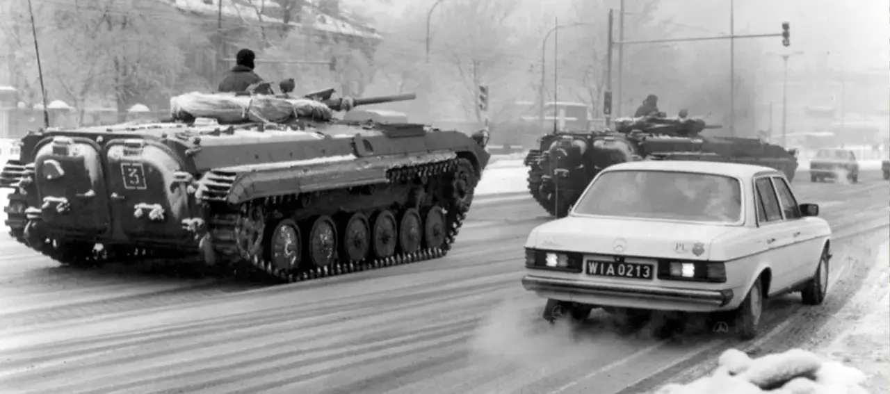 Czołgi na ulicy, biały Mercedes z tablicą WIA 0213, zimowa sceneria. To obraz z czasów stanu wojennego.