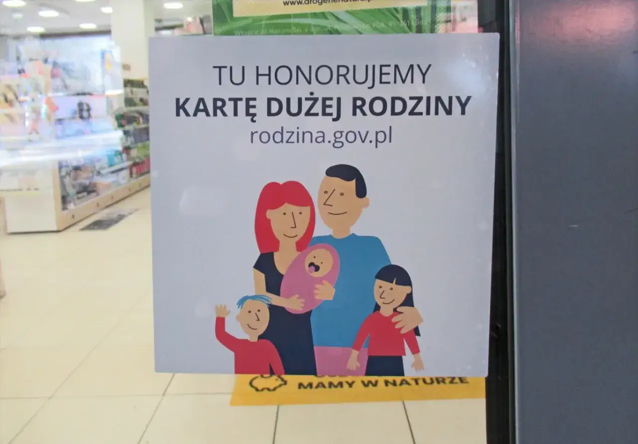 Plakat informuje, że honorowana jest karta dużej rodziny, oferując zniżki. Widnieje na nim rysunek rodziny z dziećmi.