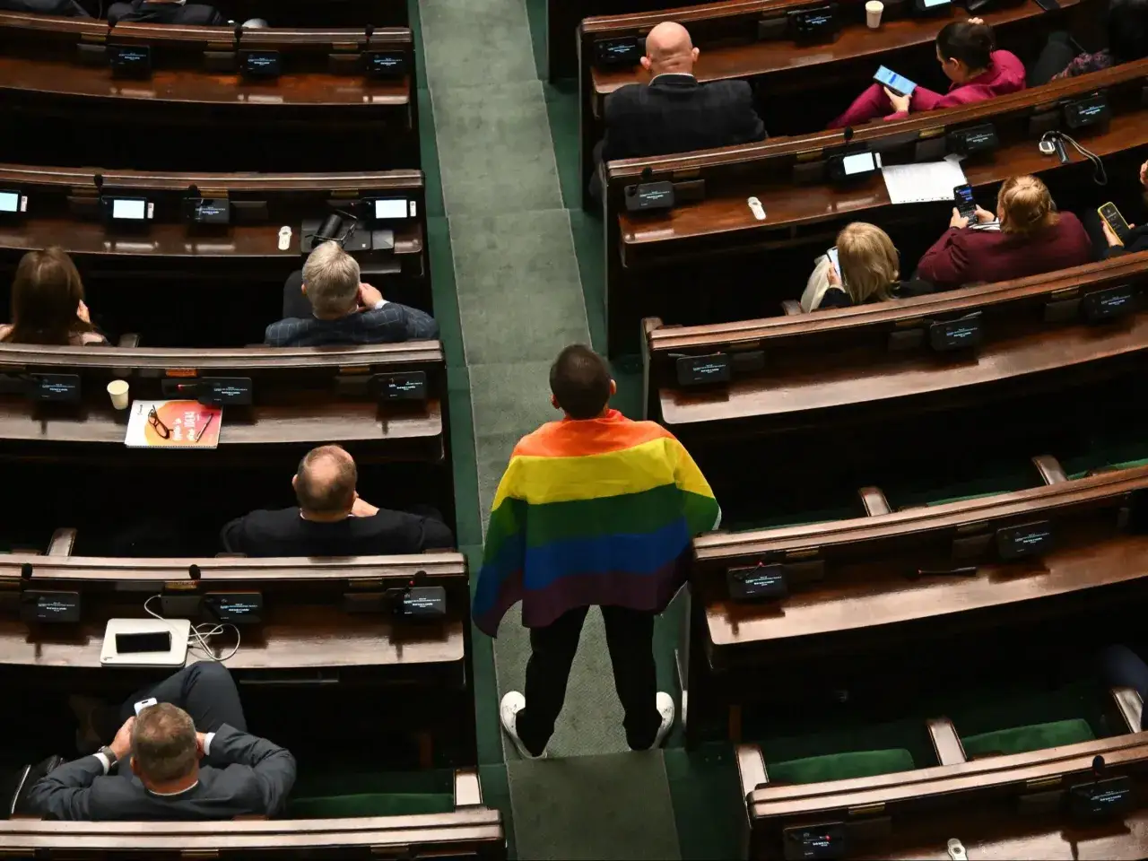 Osoba z tęczową flagą w Sejmie. Debata nad nowelizacją kodeksu karnego przez lewicę w sprawie mowy nienawiści.