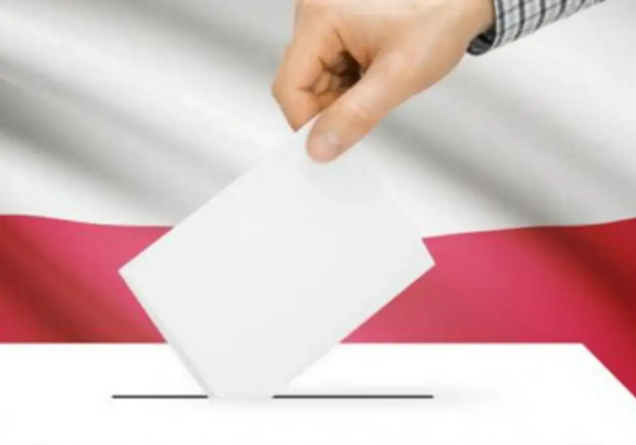 Dłoń wrzuca kartę do urny na tle polskiej flagi. Dowiedz się, jak głosować.
