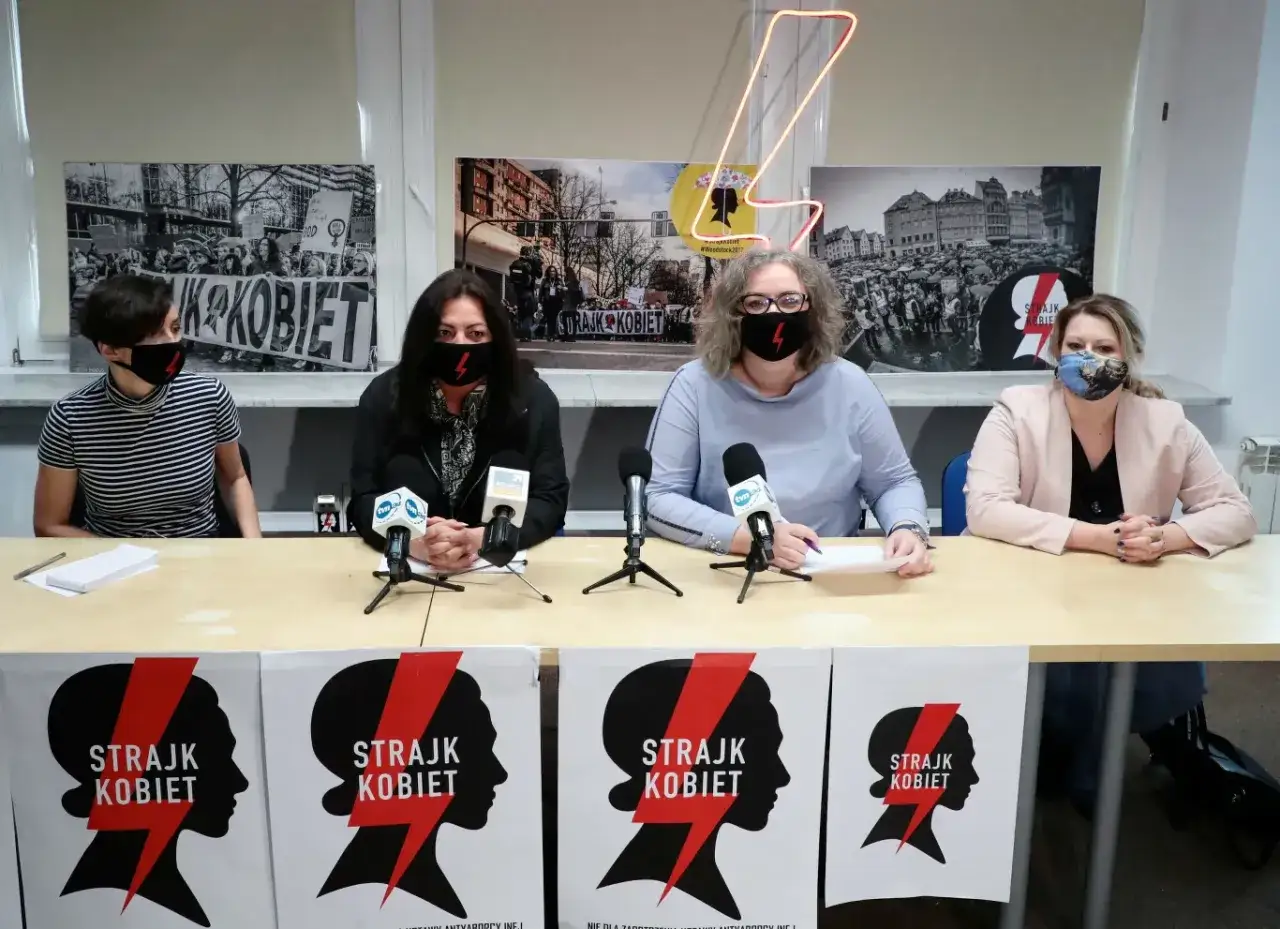 Lewica i Strajk Kobiet: jak protesty przełożyły się na poparcie partii. Kobiety w maseczkach z symbolem błyskawicy siedzą za stołem.