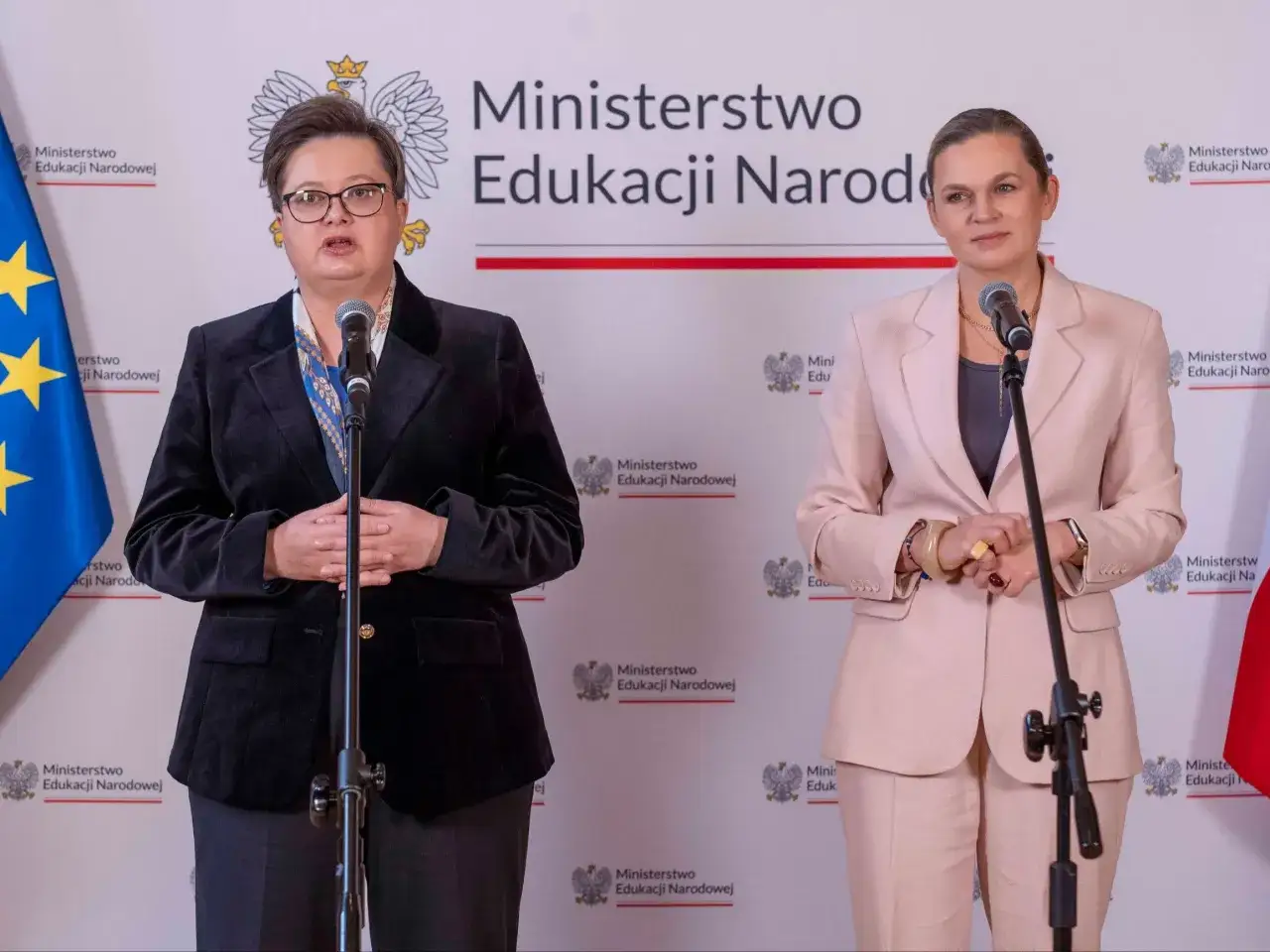 Dwie kobiety przemawiają na tle logo Ministerstwa Edukacji Narodowej. Zapowiadają reformę polskiej edukacji według założeń Polska 2050.