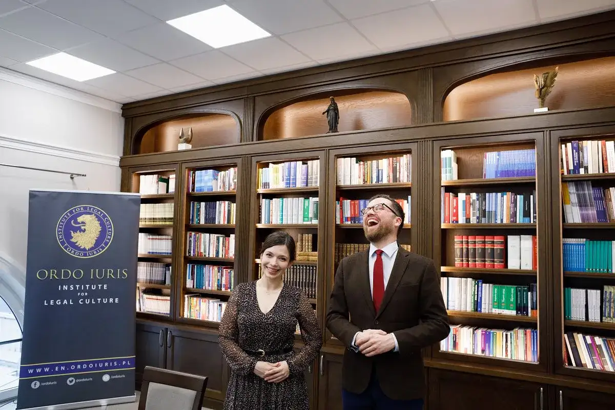 Uśmiechnięci ludzie przed regałami pełnymi książek w siedzibie Ordo Iuris.