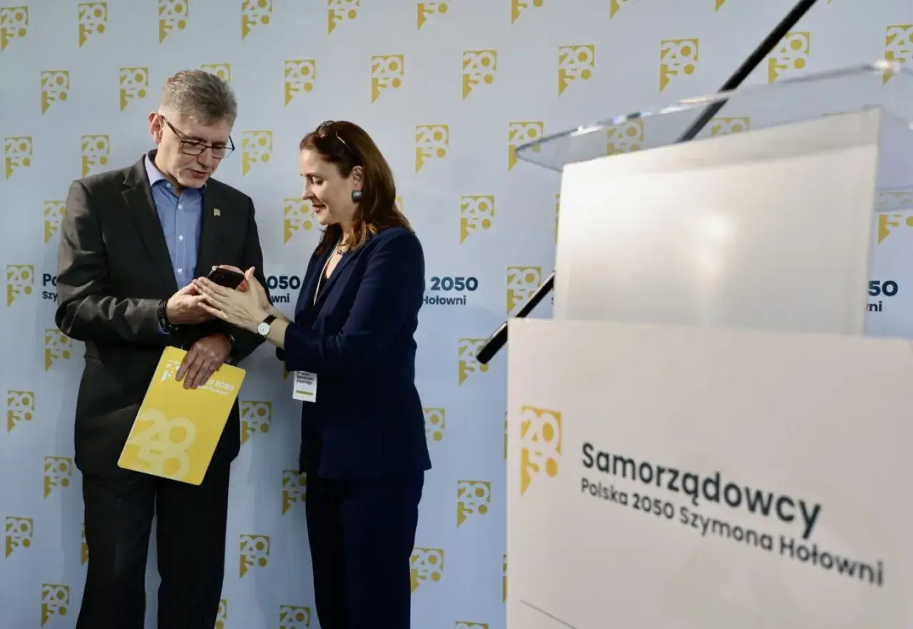 Jak Polska 2050 chce zwiększyć finansowanie samorządów terytorialnych. Dwoje polityków dyskutuje przy mównicy z logo ugrupowania.