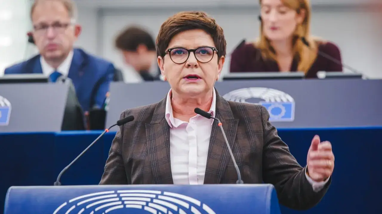 Kobieta w okularach przemawia na forum, dyskutując o konfederacji a wolności słowa i projekcie ustawy o ochronie w internecie.
