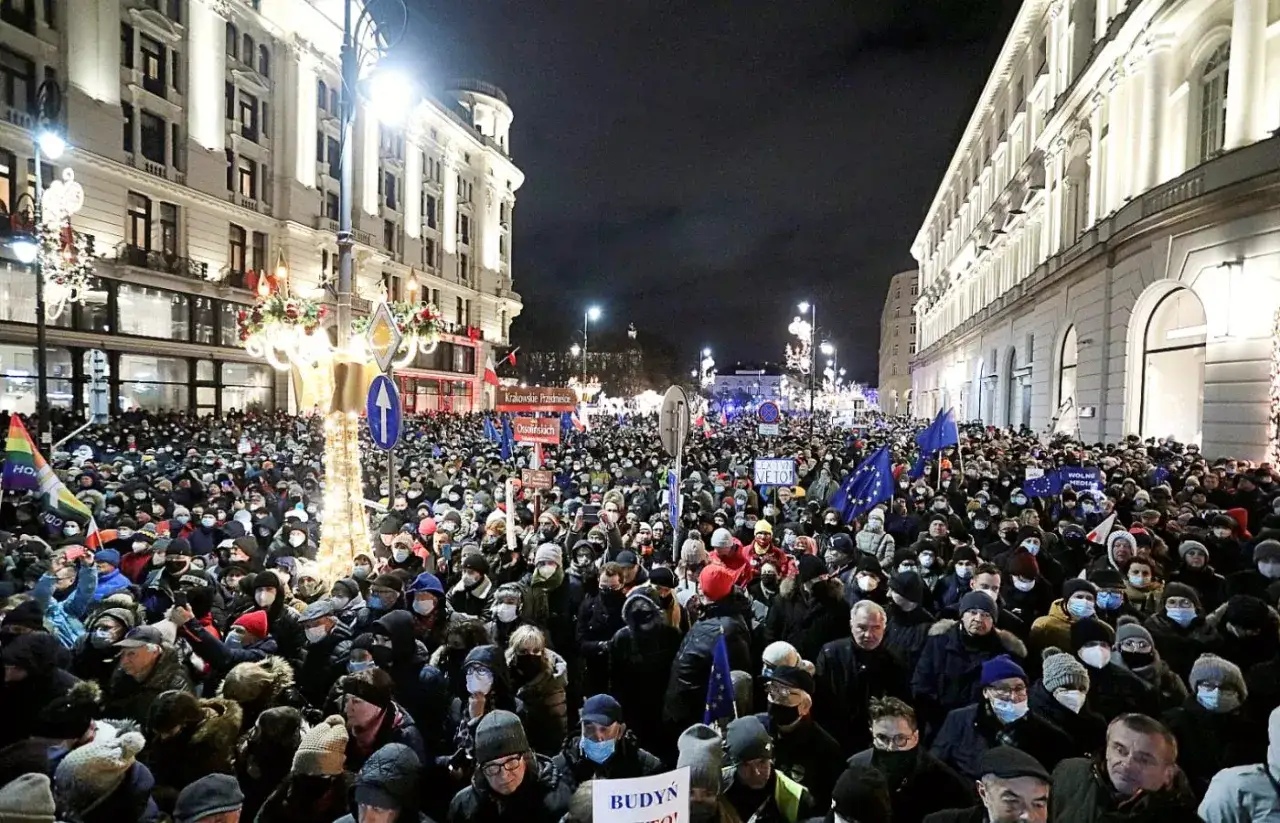 Tłum protestuje przeciwko ustawie Lex TVN, która wpłynęła na wizerunek rządu PiS. Widać flagi UE i transparenty.