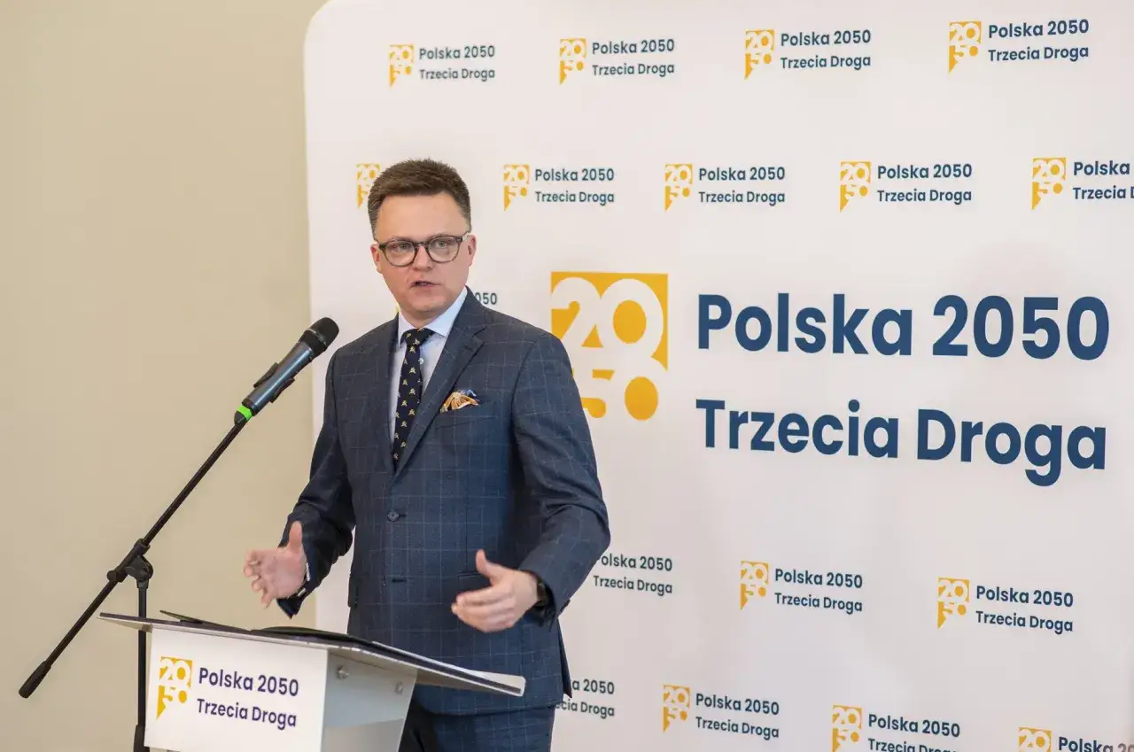 Szymon Hołownia przemawia na tle logo 