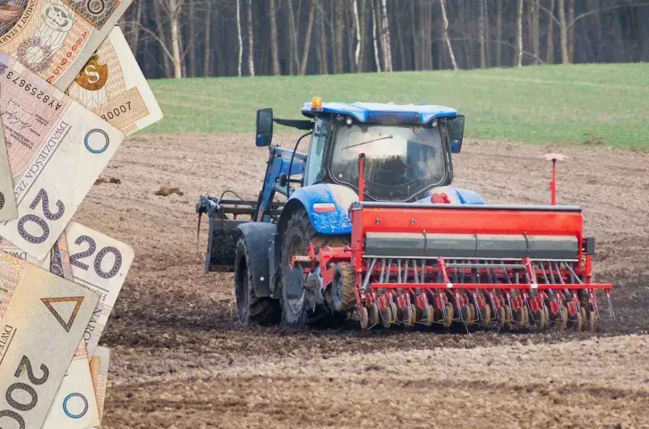 Niebieski traktor z siewnikiem na polu. W tle las. Na pierwszym planie polskie banknoty, symbolizujące dopłaty do zboża.