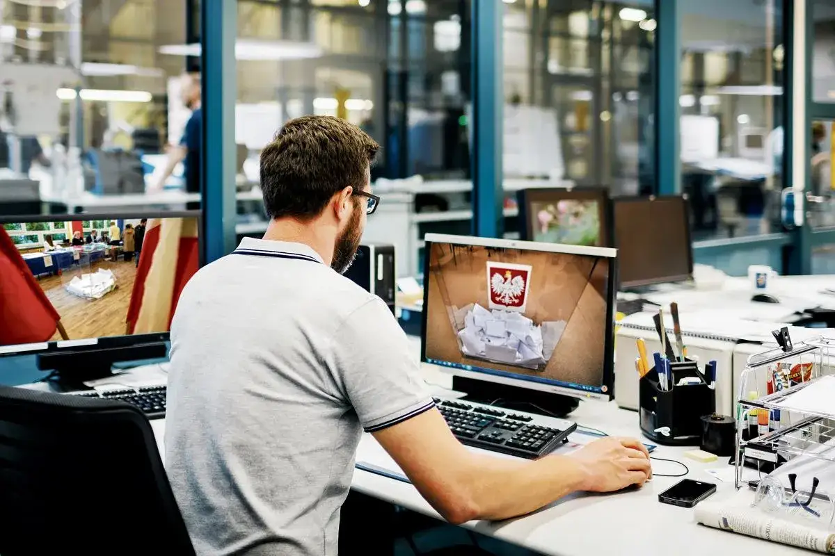 Programista analizuje propozycje Konfederacji dla branży IT i programistów B2B. Na ekranie widzi urnę wyborczą z polskim godłem.