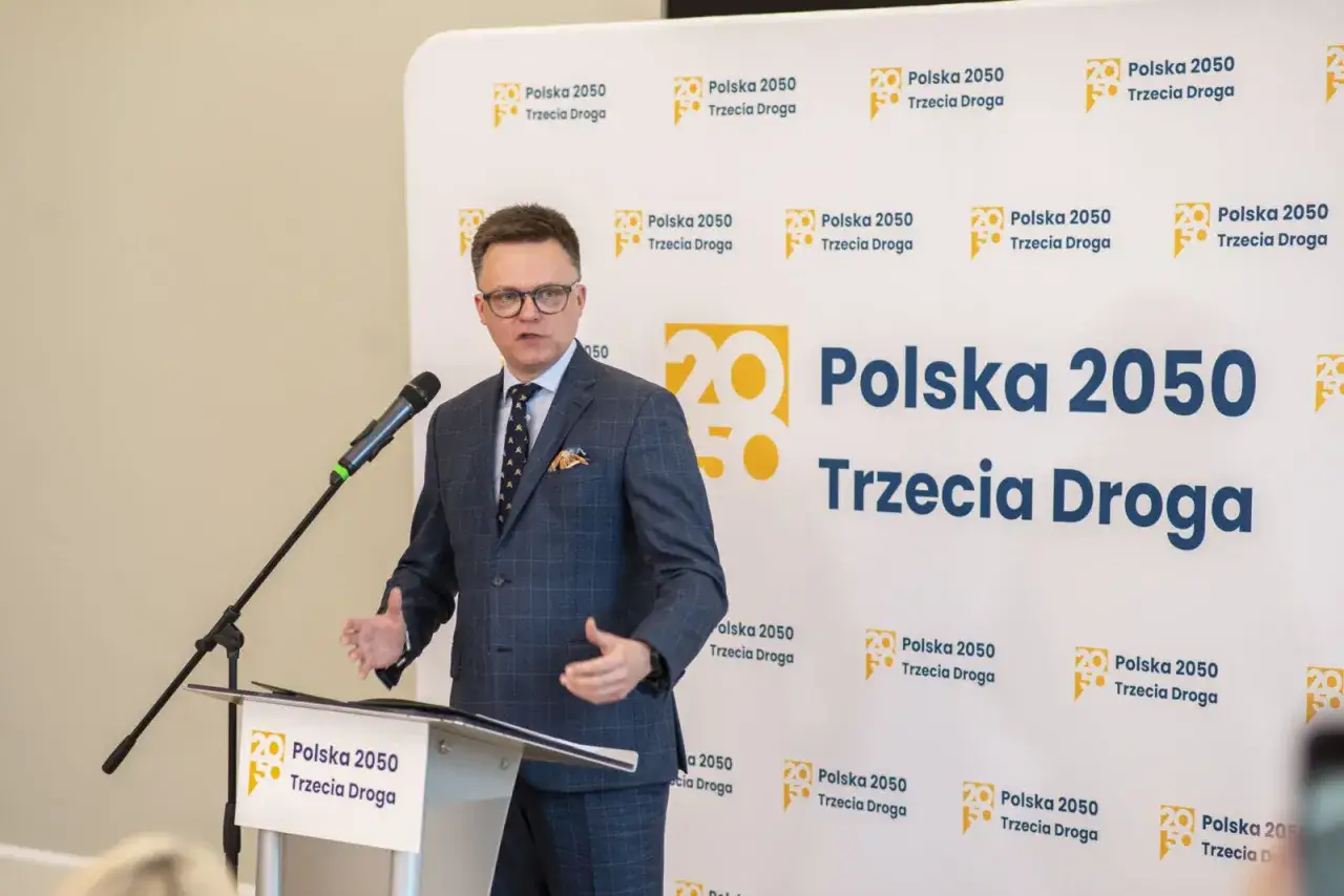 Szymon Hołownia przemawia na tle logo 