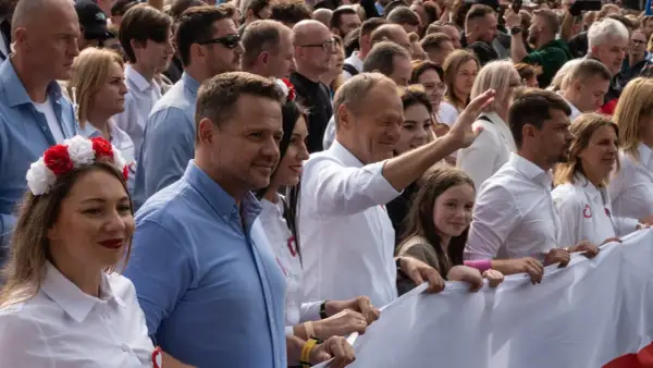 Uśmiechnięty Donald Tusk i tłum ludzi z biało-czerwonymi akcentami, wspierający platformę obywatelską.