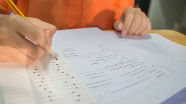 Ręka z ołówkiem zaznacza odpowiedzi na arkuszu testowym. Zastanawiasz się, ile punktów na maturze z matematyki zdobędziesz?