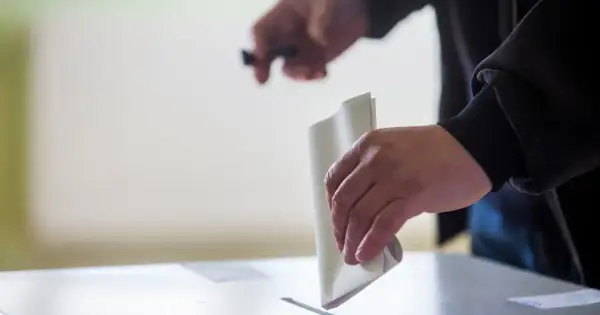 Ręka wrzuca kartę do głosowania do urny. To ważny moment, pokazujący, jak głosować.
