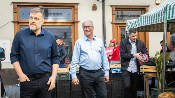 Mężczyźni w garniturach i koszulach, jeden z nich trzyma materiały wyborcze Lewicy.