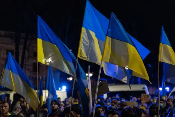 Zwolennicy pomocy militarnej dla Ukrainy i polityki obronnej kraju, z ukraińskimi flagami na nocnym wiecu.