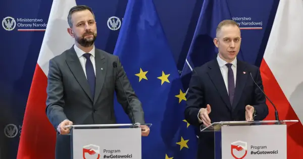 Dwóch mężczyzn w garniturach przemawia za mównicami. Tło stanowią flagi Polski i UE. Tematem dyskusji mogło być to, jak rządy PiS zmieniły strukturę polskiego wojska.