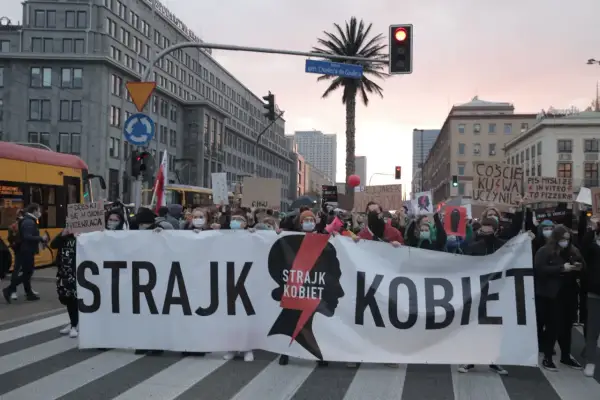 Protest Strajku Kobiet na ulicach Warszawy. Uczestnicy niosą transparent "STRAJK KOBIET". Jak protesty strajku kobiet wpłynęły na poparcie PiS?