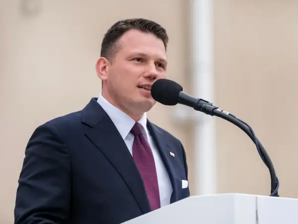 Sławomir Mentzen w garniturze przemawia do mikrofonu. Jego majątek budzi zainteresowanie.